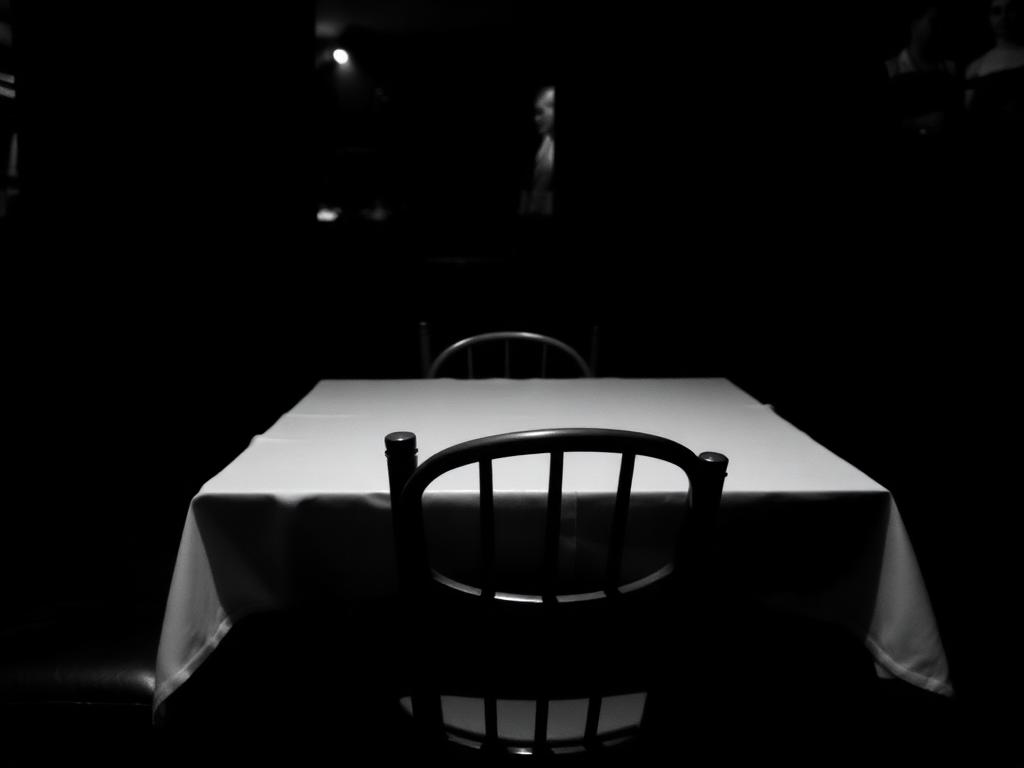 Empty restaurant table with a single chair in low light