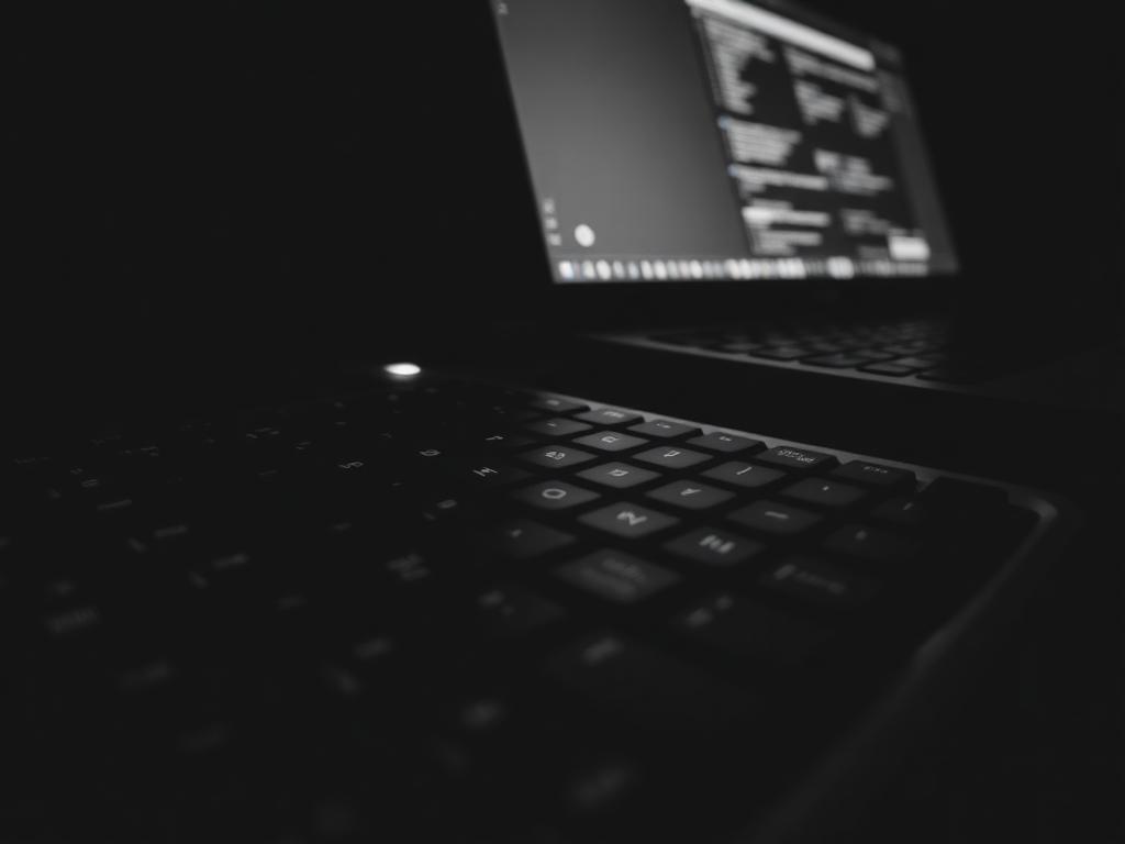 Mechanical keyboard and laptop lit dramatically in the dark